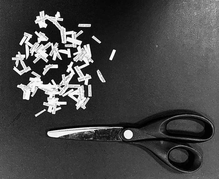 A black and white image of a scissor and the scraps of paper with the term chartjunk written on them.