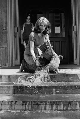A black and white image of Mierle Laderman Ukeles cleaning the steps of a building.